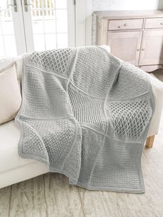 a living room with a white couch and a crocheted blanket on top of it