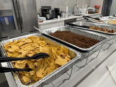 three trays filled with different types of food on top of a counter in a kitchen