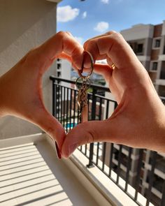 two hands making a heart shape with the keys to each other in front of a balcony