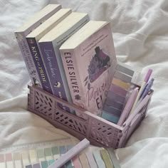 several books in a basket on a bed next to a pencil and ruler with color swatches