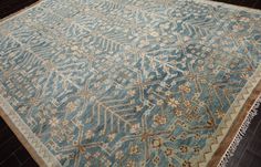 a blue rug with an intricate design on the top and bottom, sitting on a wooden floor