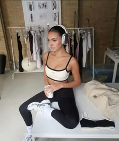 a woman sitting on top of a bed wearing headphones and holding a coffee cup