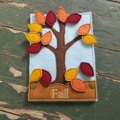 a felt fall tree with leaves and numbers on it, sitting on a wooden surface