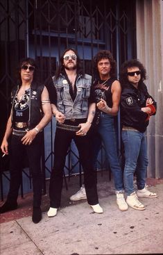 the band kiss posing for a photo in front of an iron gate