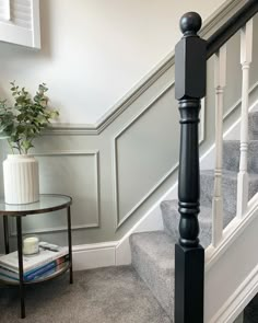 there is a plant on the table next to the stair railing in this room with gray carpet