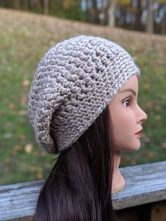 a mannequin head wearing a crocheted hat on top of a wooden bench