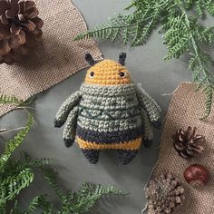 a crocheted stuffed animal sitting on top of a table next to pine cones