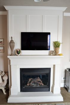 a flat screen tv mounted on top of a white mantle in front of a fire place