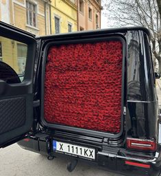 the back end of a black car with red carpet on it's trunk and door