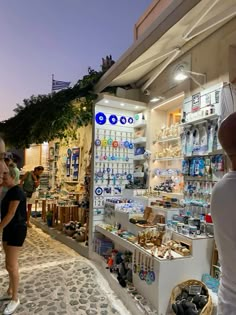 people are looking at items on display in a storefront with stone floors and cobblestone walkways