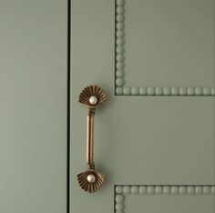 a close up of a door handle on a green door with beaded trimmings