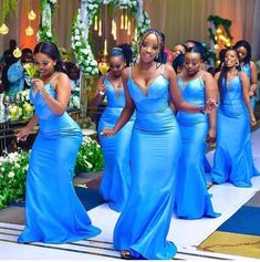 a group of women in blue dresses walking down a runway