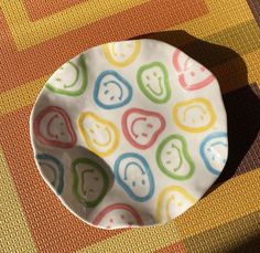 a colorful plate sitting on top of a table next to a yellow and red rug