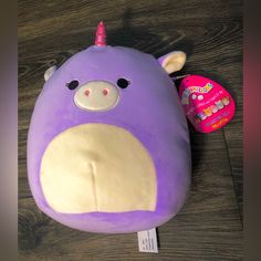 a purple stuffed animal with a unicorn horn on it's head sitting on a wooden floor