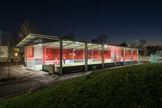 a bus stop sitting on the side of a road at night with its lights on