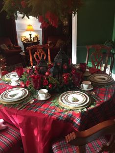 the table is set for christmas dinner with red and green plaid cloths on it