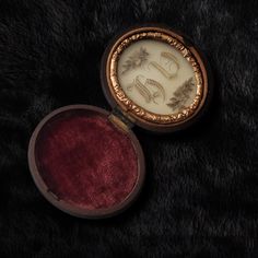 an antique pocket watch is sitting on a black fur covered surface with its case open