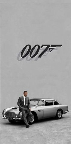 a man sitting on top of a car next to a james bond movie poster that reads 007