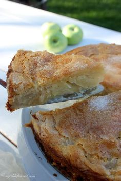 a close up of a pie on a plate with an apple in the back ground