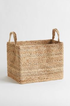 a large woven basket with handles on the bottom and sides, sitting against a white background