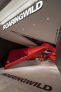 the entrance to roaring wild is lit up with red stairs and black lettering that read roaring wild