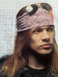 a man with long hair wearing a pink bandana and black eye patch on his forehead