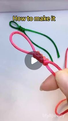 someone is making something out of yarn and string with scissors on the end, which are colored red, green, and pink