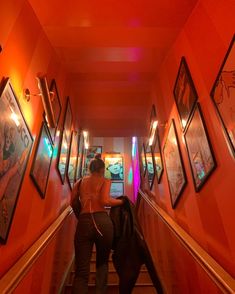 a woman walking down an escalator with pictures on the wall