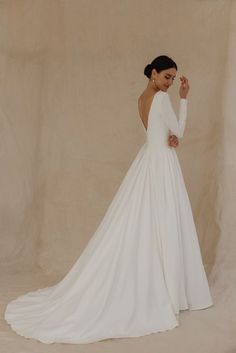 a woman in a white wedding dress posing for the camera with her hand on her hip