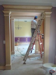 a man standing on a ladder in a room that is being painted purple and yellow