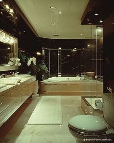 a large bathroom with two sinks and a bathtub in the middle, surrounded by glass walls