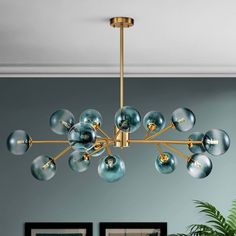 a modern chandelier with blue glass balls hanging from the ceiling in a living room