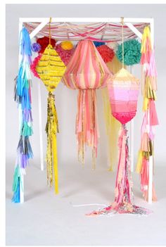 several colorful lanterns hanging from a white structure with tassels on the sides and fringes around them