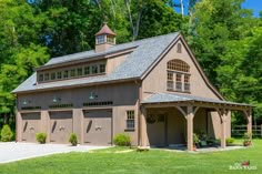 a large brown garage sitting in the middle of a lush green field with lots of trees