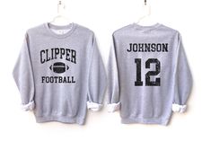 Customize this football shirt to meet your needs! Choose from short sleeve, long sleeve, hoodies, and crewneck sweatshirts and add your team/mascot and name/number! Other color options and styles are available. If you don't see what you're looking for send us a message! The shirts are a UNISEX retail fit - they are more of a relaxed fit and may run a little large on women and those with a smaller frame. Make sure to see the size and fit charts (last images) to confirm the best fit for you. We re Football Season Fan Merchandise Long Sleeve Hoodie, Fan Merchandise Long Sleeve Hoodie For Football Season, Football Season School Spirit Long Sleeve Sweatshirt, School Spirit Long Sleeve Sweatshirt For Football Season, Collegiate Long Sleeve T-shirt For Football Season, Long Sleeve Sports Fan T-shirt, Long Sleeve Hoodie For Football Season, Football Season Crew Neck Hoodie, Football Season Hoodie With Letter Print For Sports Events