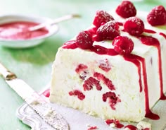 a piece of cake with raspberries on top and some sauce in the background