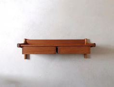 a wooden shelf mounted to the side of a wall with two drawers on each end