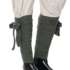 the legs of a woman wearing black boots and green pants with ruffles on them