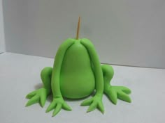 a green frog sitting on top of a white table