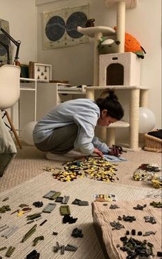 a woman kneeling down on the floor looking at pieces of art that she made out of legos