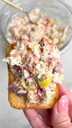 a hand holding a cracker filled with crab salad