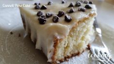 a piece of cake with white frosting and chocolate chips on top is sitting on a plate