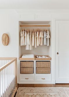 a baby's nursery closet with clothes hanging on the rails and wicker baskets