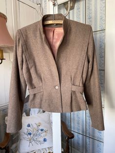 This very flattering fitted jacket in medium brown is made from a blend of polyester, wool and other fibres. It has the original button in the front, pleat detailing on the front and shoulders, and a belt detail that goes from front to back, making a bit of a peplum at the bottom. Made by Dominique; marked size 7/8. The measurements, taken with the jacket lying flat, are: shoulder to shoulder, 17 inches; armpit to armpit, 19 inches; sleeves, 24 inches; waist, 14 inches; length, 22 inches; bottom edge, 20 inches. In very good condition. Fitted Jacket, Brown Shorts, Cropped Jacket, Workout Jacket, Short Jacket, Medium Brown, Crop Jacket, Shoulder To Shoulder, Wool Blend