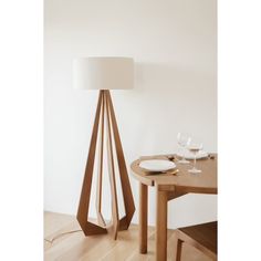 a table with a plate and wine glasses on it next to a lamp that is shaped like a cone