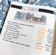 an open notebook with the words october written in orange and white stars on it, next to a blue paisley background