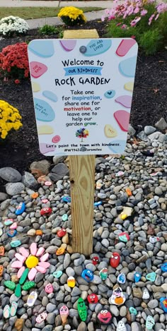 a rock garden sign surrounded by flowers and rocks