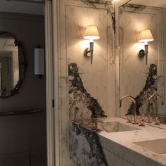 a bathroom with marble counter tops and two sinks in front of large mirrors on the wall