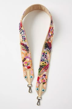 a lanyard strap with flowers and birds on it, attached to a white wall