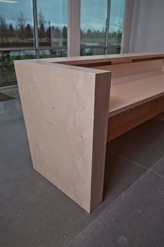 a bench made out of plywood with windows in the background